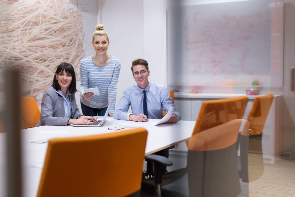 Dos mujeres y un hombre en reunión de trabajo, sonriendo